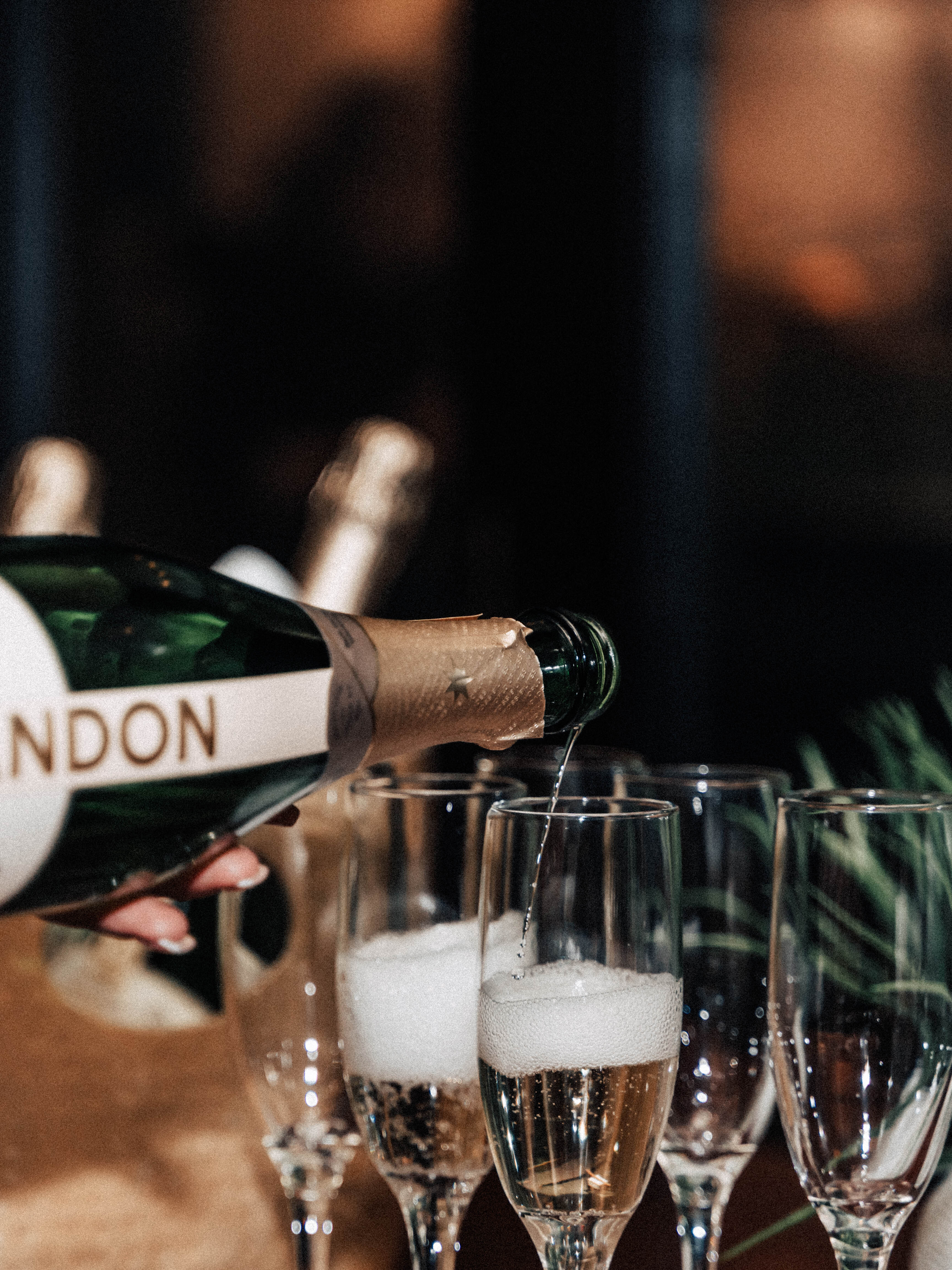Champagne being poured into a row of flutes at an EA Society dinner.