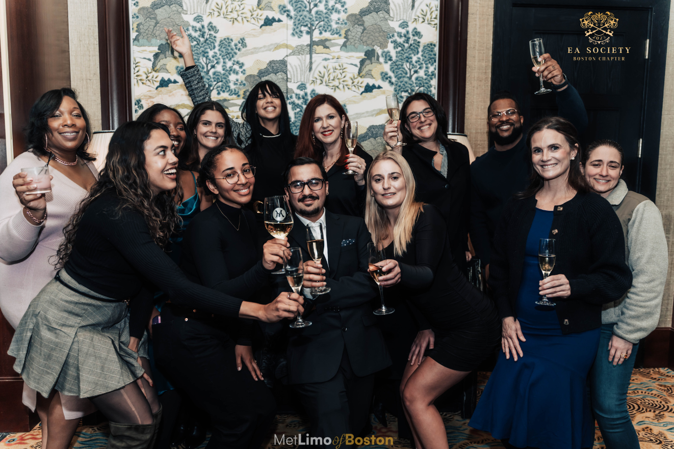 EA Society members at a private dinner with the EA Society branding visible in the background.